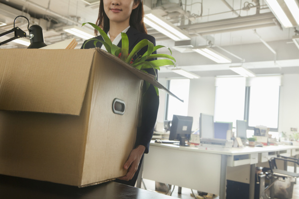 Деловая женщина перевозит коробку с офисными принадлежностями
 - Фото, изображение