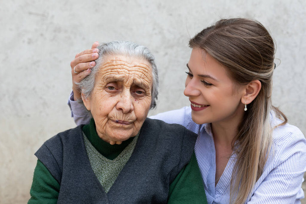 Młoda przyjazna kobieta obejmująca starszą panią na świeżym powietrzu - czas spędzony razem - Zdjęcie, obraz