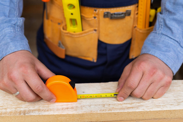 Close up picture of carpenters hands measuring plank - DIY renovation at home - Foto, immagini