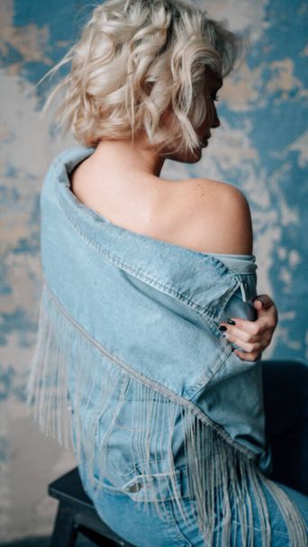 blondynka piękne młoda kobieta w stylowe ubrania pozowanie w poddaszu wnętrza   - Zdjęcie, obraz