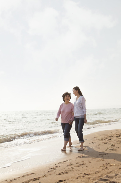 бабуся і внучка, гуляючи на пляжі - Фото, зображення