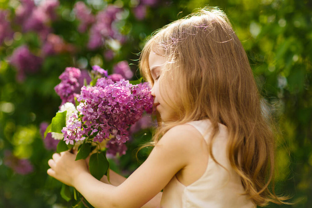 kid girl near lilac flowers snuff bouquet - Фото, зображення