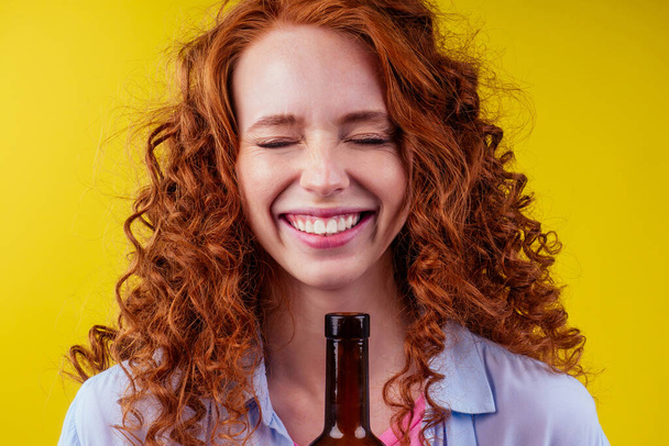 redhaired ginger woman holding non alcoholic alcohol wine bottle and feeling good emotions - Фото, зображення