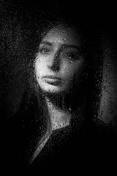 A slender brunette girl in a black dress stands on a gray background. - Valokuva, kuva