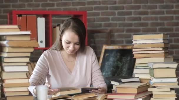 Příprava zkoušky. žena čte učebnici mezi mnoha knihami. krásná mladá dívka sedí v pokoji doma u stolu a čtení knihy. studentské studium doma. domácí vzdělání. koncepce moderního vzdělávání - Záběry, video
