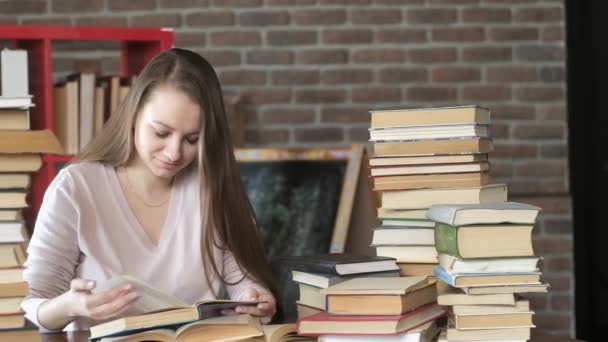 Sınav hazırlığı. Kadınlar bir sürü kitap arasında ders kitabı okurlar. Güzel bir genç kız evinde bir masada oturuyor ve sayfalarca kitap sayfalarını karıştırıyor. Öğrenciler evde okuyor. ev eğitimi. - Video, Çekim
