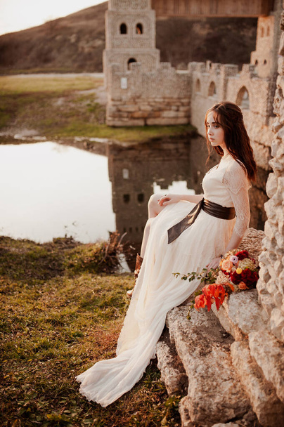 The bride with a bouquet on beautiful large lake background at sunset. Rustic Wedding - Foto, imagen