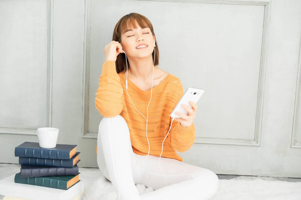 Beautiful asian short haired girl  wore Orange sweater, listening to music and read book on vacation at home Sit and read a book,lifestyle at home - Photo, Image