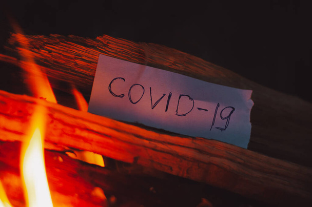 Un foglio di carta con l'iscrizione COVID-19 in un incendio
 - Foto, immagini