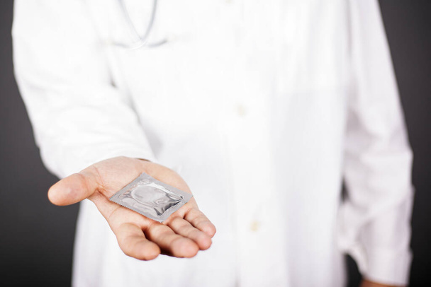 Un medico offre un preservativo per il sesso sicuro. protezione dalle malattie sessualmente trasmissibili
 - Foto, immagini