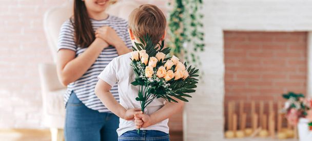 Boy holding a bouquet of flowers behind his back - Photo, Image