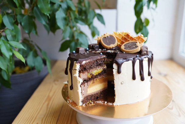 Pastel de chocolate cortado con relleno de crema de caramelo en mesa de madera
 - Foto, imagen
