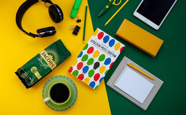 Kyiv, Ukraine - April 16, 2020: Jacobs coffee on the desktop. Coffee packing. Workspace. Layout. Stationery on a bright yellow and green background. Work remotely and drink coffee. - 写真・画像