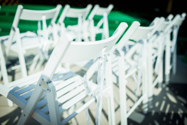 白い折りたたみ木製の椅子Terjeは屋外の行に立っています。結婚式 - 写真・画像