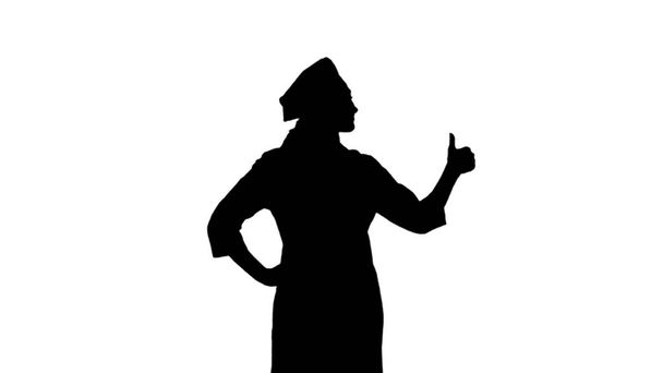 Πορτρέτο της μαύρης σιλουέτας του κοριτσιού μάγειρας σε toque, ποδιά στέκεται και δείχνει σαν σημάδι απομονώνονται σε λευκό φόντο - Φωτογραφία, εικόνα