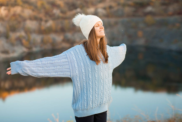 Retrato de inverno de mulher sorrindo em chapéu branco com grande bubo faz cara engraçada ao ar livre - Foto, Imagem