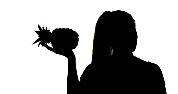 silhouet van vrouw figuur met ananas fruit in handen op witte geïsoleerde achtergrond, concept vitaminen en gezond voedsel, vrouwelijke schoonheid - Foto, afbeelding