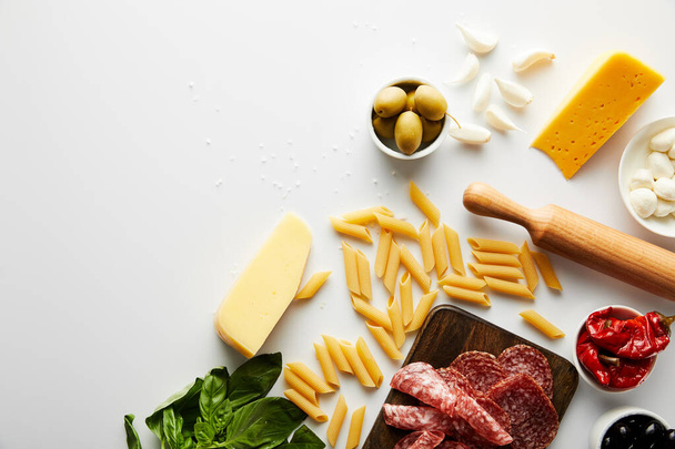 Top view of meat platter, rolling pin, pasta and ingredients on white background  - Photo, Image