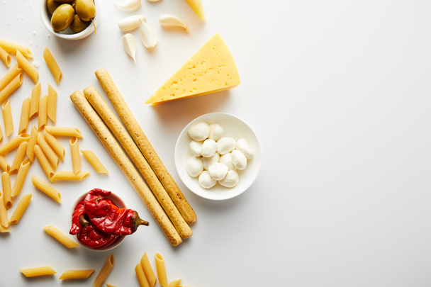 Top view of breadsticks, pasta and ingredients on white background  - 写真・画像