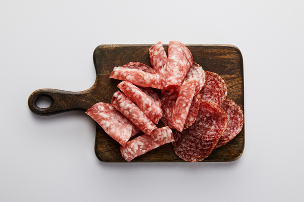 Top view of salami slices on board on white background  - Фото, зображення