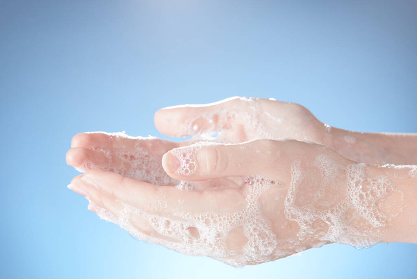 Horizontal shot of woman's hands in soapsuds, on blue background close-up. - Fotografie, Obrázek