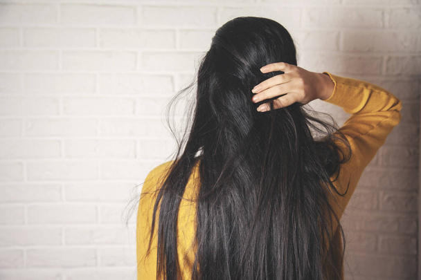 γυναίκα χέρι στα μαλλιά σε τούβλο τοίχο φόντο - Φωτογραφία, εικόνα
