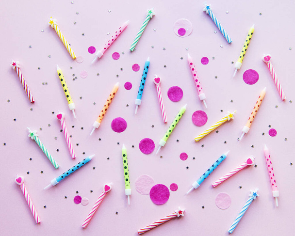 Šťastné narozeniny koncept, konfety a pestrobarevné svíčky na růžovém pozadí. byt ležel, horní pohled - Fotografie, Obrázek