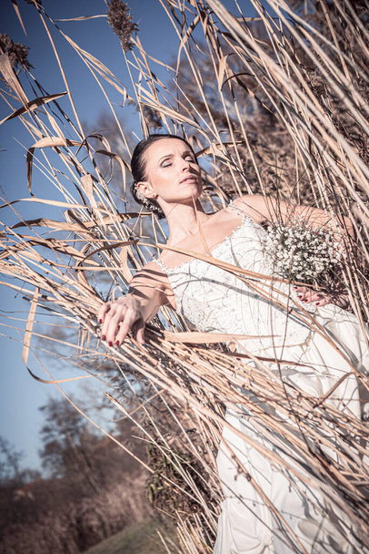 outdoor portrait of a bride with bridal bouquet in a wedding dress - Fotó, kép
