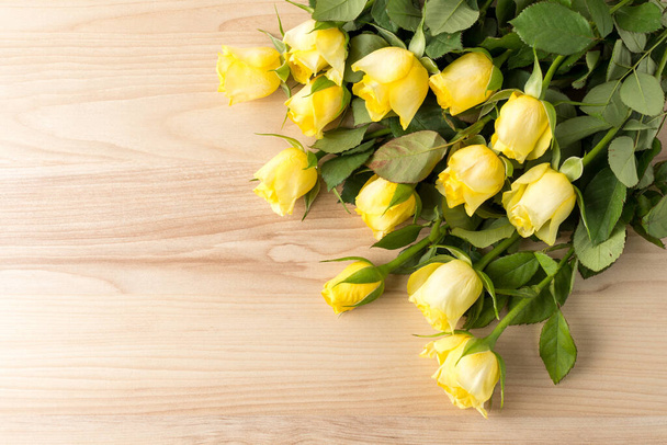 Vista lateral de muchas pequeñas flores de color amarillo vivo y hojas verdes sobre una mesa de madera cruda, hermoso fondo floral interior fotografiado con pequeño enfoque
 - Foto, imagen