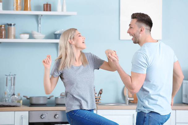 Ευτυχισμένο χορευτικό νεαρό ζευγάρι στην κουζίνα - Φωτογραφία, εικόνα