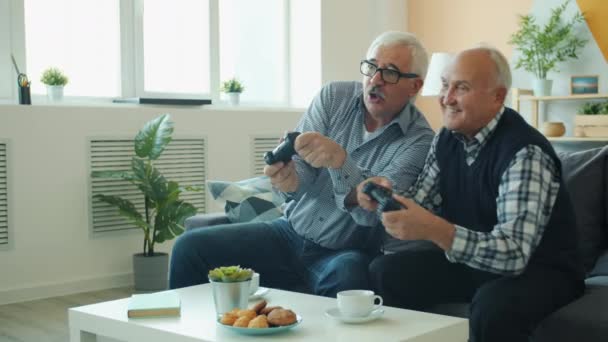 Slow motion of joyful friends senior men playing video game then doing high-five - Video