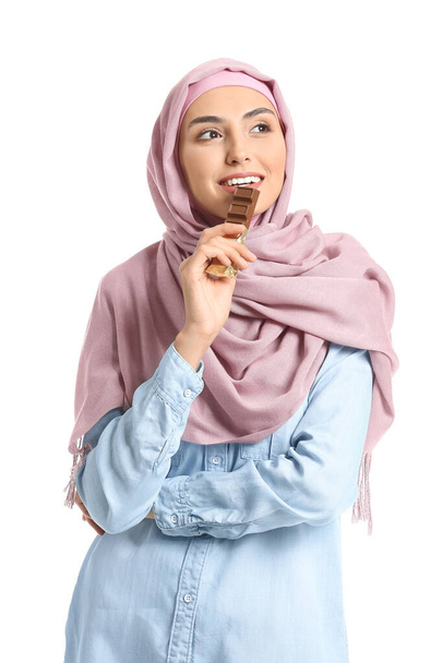 Güzel Müslüman kadın beyaz arka planda lezzetli çikolata yiyor. - Fotoğraf, Görsel