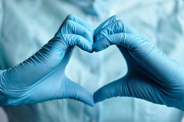 Um médico de luvas médicas azuis tira um coração das mãos. Fechar
. - Foto, Imagem