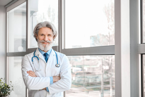 Portret van oudere mannelijke arts in kliniek - Foto, afbeelding