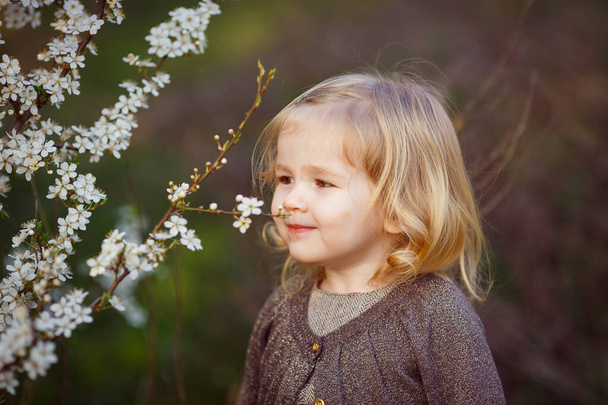 small blond girl in thickets of blooming bushes. - Foto, Imagen