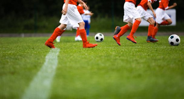 Futbol takımı toplarla egzersiz yapıyor. Maçtan önce takım çalışması sırasında genç sporcular. Kırmızı spor giyimli genç oyuncular topla egzersiz yapıyor. - Fotoğraf, Görsel