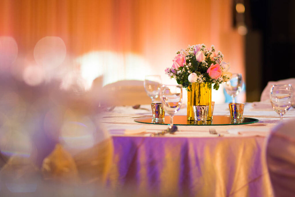Rose Florist in Glasvase Dekoration auf dem Esstisch mit Besteck und Kerze indische Hochzeit Setup drinnen mit dekorativen Lichtern und schönen Bokeh. - Foto, Bild