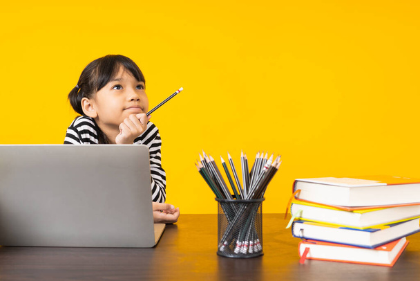 молодая девушка, которая думает, что учится на ноутбуке на желтом фоне, изучает, ищет и записывает видео в Coronavirus и covid 19.
 - Фото, изображение