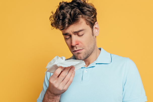 Portrait of sick man with napkins and closed eyes isolated on yellow - Photo, Image