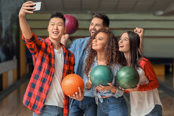 Friends taking selfie while playing bowling in club - Фото, изображение