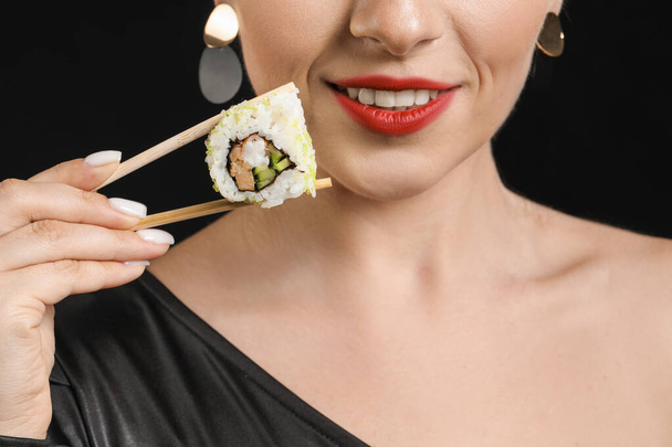 Beautiful woman with tasty sushi on dark background, closeup - 写真・画像