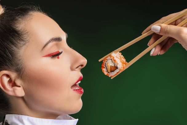 Beautiful woman with tasty sushi on dark background - Foto, Imagem
