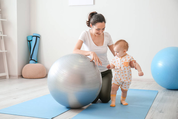 Mladá sportovní matka a její dítě dělá cvičení s fitball doma - Fotografie, Obrázek