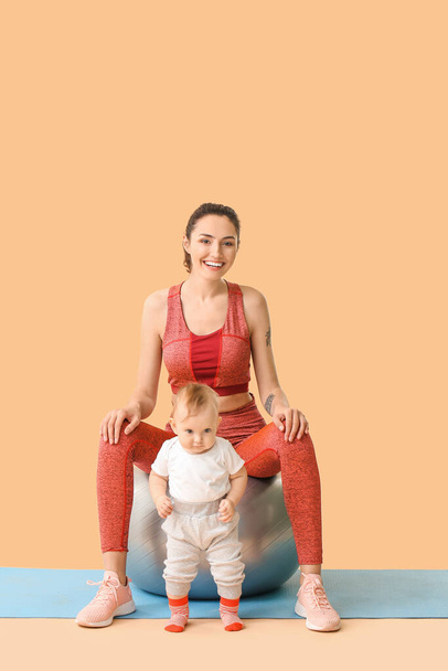 Молодая спортивная мать и ее ребенок делают упражнения с фитболом на цветном фоне
 - Фото, изображение
