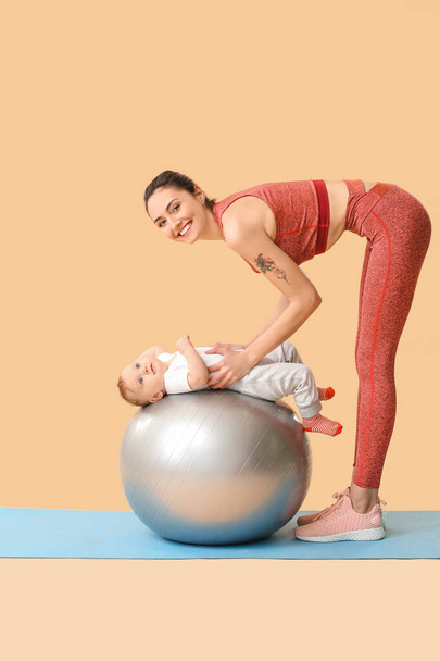 Jeune mère sportive et son bébé faisant des exercices avec fitball sur fond de couleur
 - Photo, image