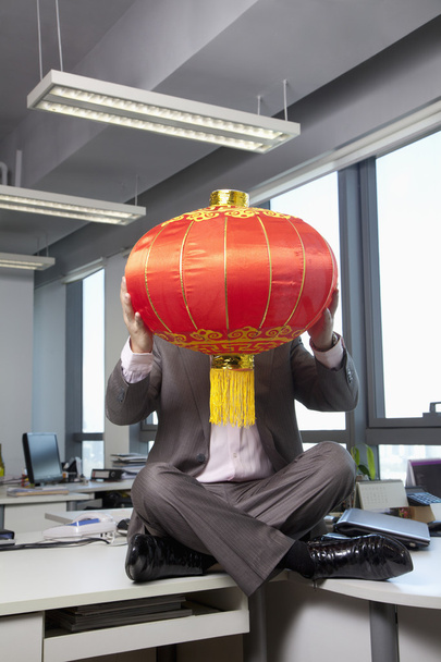 Empresário segurando lanterna chinesa na frente da cara
 - Foto, Imagem
