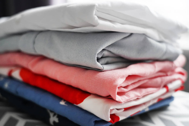 pilha de camisas multicoloridas bem dobradas em uma tábua de engomar
 - Foto, Imagem