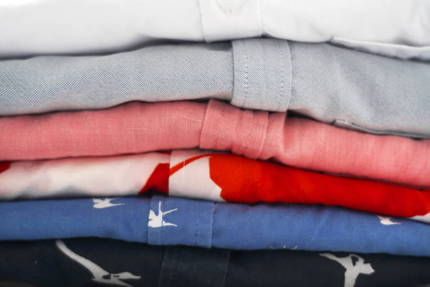 hromádka úhledně složených pestrobarevných košil na žehlícím prkně - Fotografie, Obrázek