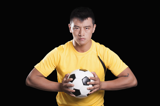 Jalkapalloilija pitää palloa rintaan
 - Valokuva, kuva