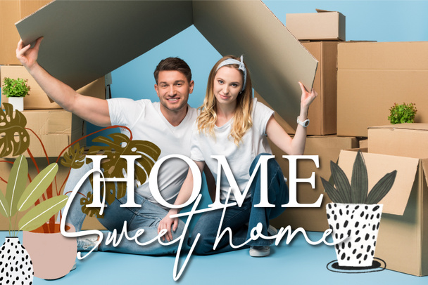 beautiful couple holding carton roof over heads while sitting on blue with cardboard boxes for relocation, home sweet home illustration - Photo, Image